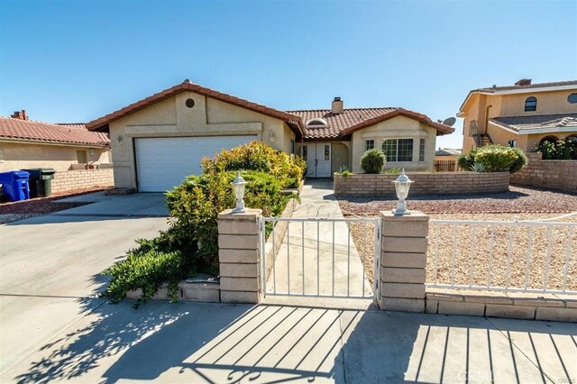 mediterranean / spanish house with driveway, an attached garage, a chimney, a fenced front yard, and a tile roof