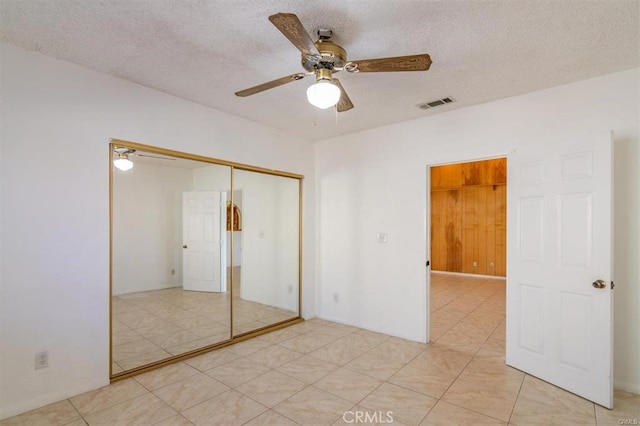 unfurnished bedroom featuring a closet, visible vents, a textured ceiling, and ceiling fan