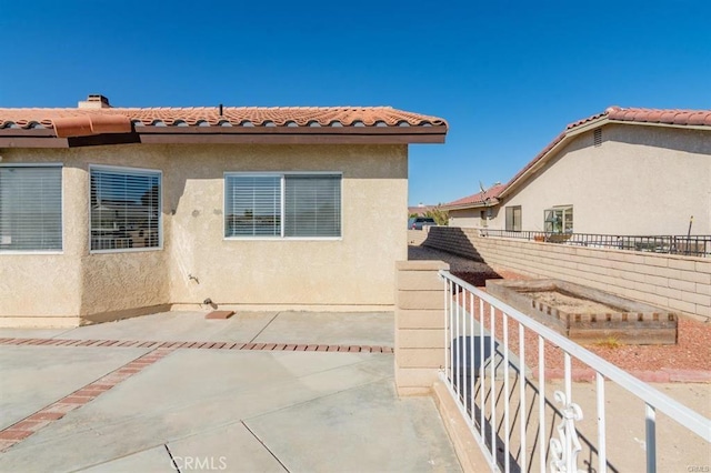 exterior space featuring a patio, fence, a tile roof, and stucco siding