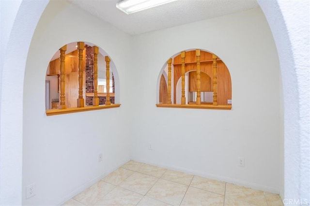 unfurnished room featuring baseboards, tile patterned flooring, and a textured ceiling