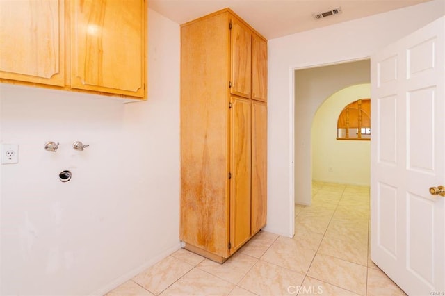 laundry area featuring visible vents, arched walkways, and light tile patterned floors