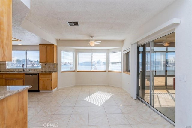 kitchen with decorative backsplash, visible vents, ceiling fan, light stone counters, and stainless steel dishwasher