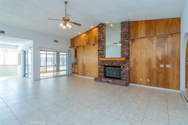 unfurnished living room with high vaulted ceiling, ceiling fan, wooden walls, visible vents, and a fireplace