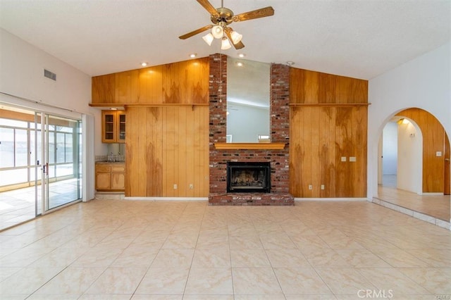 unfurnished living room with visible vents, wood walls, and high vaulted ceiling