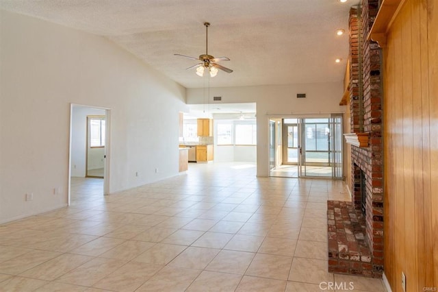 unfurnished living room featuring light tile patterned flooring, high vaulted ceiling, a ceiling fan, and a brick fireplace