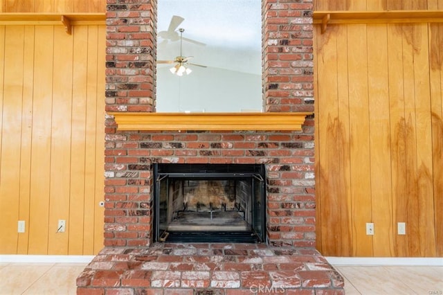 details featuring ceiling fan, baseboards, a brick fireplace, and wood walls