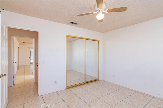 unfurnished bedroom featuring light tile patterned floors, visible vents, a closet, and a textured ceiling