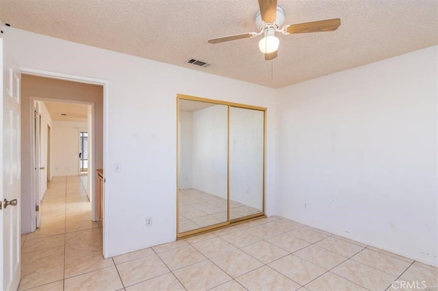 unfurnished bedroom featuring light tile patterned floors, a textured ceiling, a closet, and visible vents