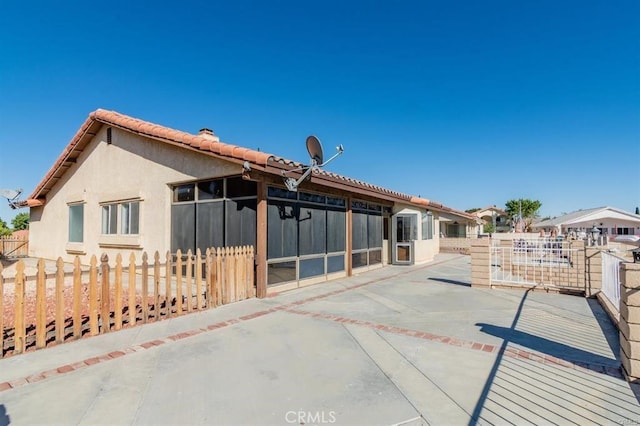 back of house featuring stucco siding, a tile roof, fence, and a patio