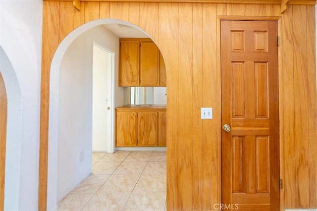 corridor with arched walkways and light tile patterned flooring