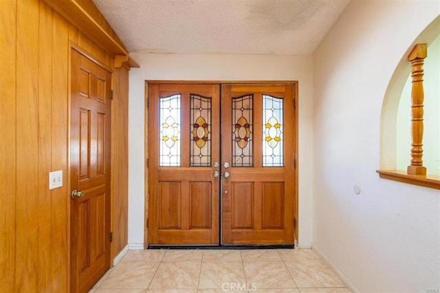 foyer with light tile patterned floors, french doors, baseboards, and a textured ceiling