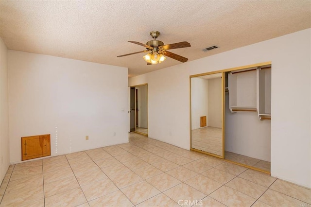 unfurnished bedroom featuring light tile patterned floors, a ceiling fan, visible vents, and a textured ceiling