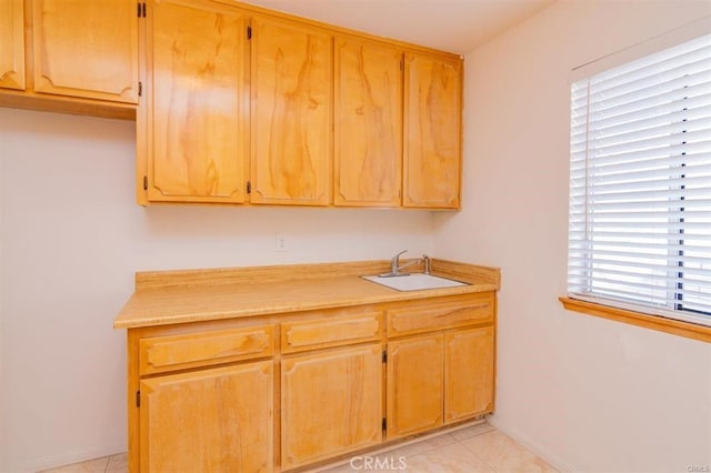 kitchen with light countertops, a sink, and baseboards