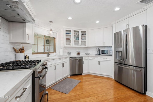 kitchen with light wood-type flooring, under cabinet range hood, appliances with stainless steel finishes, and white cabinets