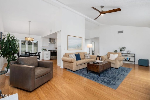 living room with ceiling fan with notable chandelier, high vaulted ceiling, light wood-type flooring, and visible vents