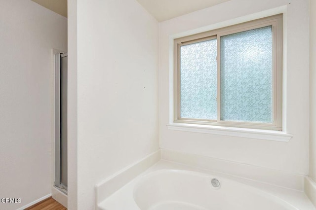 bathroom featuring a stall shower and a bath