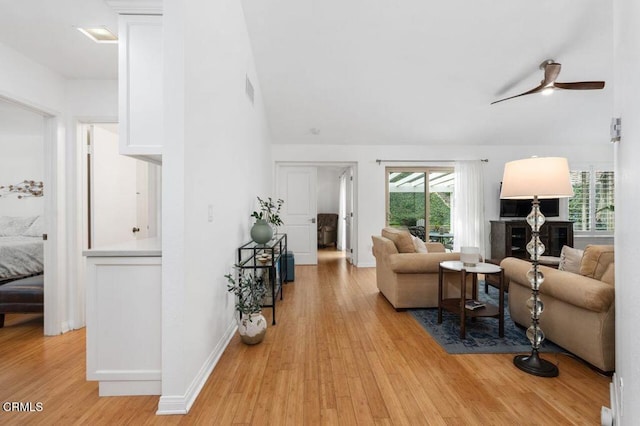living area with light wood-type flooring, a ceiling fan, baseboards, and high vaulted ceiling