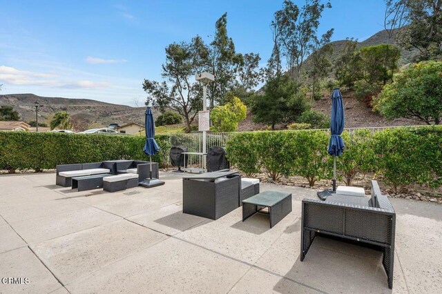 view of patio featuring an outdoor living space, a mountain view, a fenced backyard, and a grill