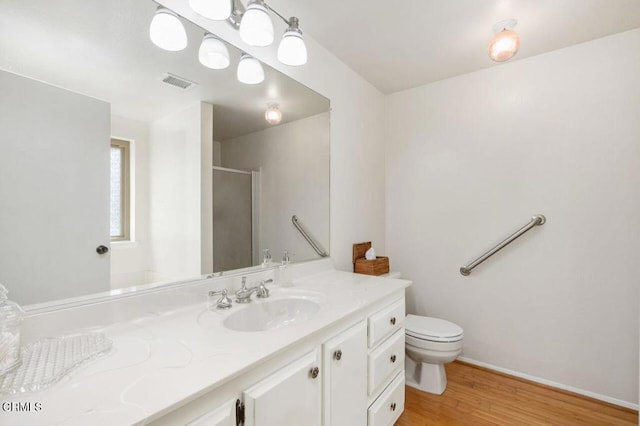 full bath with a stall shower, wood finished floors, vanity, baseboards, and toilet