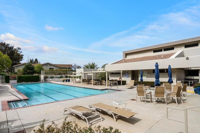 community pool with a patio area and fence