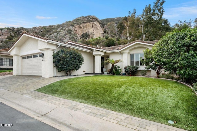 ranch-style house with driveway, a front lawn, a garage, stucco siding, and a tile roof