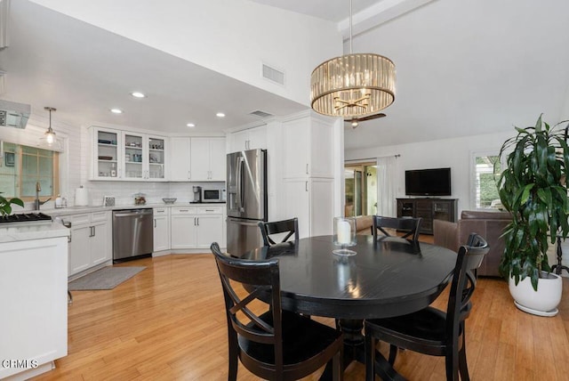 dining space featuring a towering ceiling, light wood finished floors, recessed lighting, and a chandelier