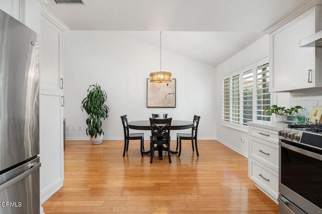 dining area featuring light wood-type flooring, lofted ceiling, and baseboards