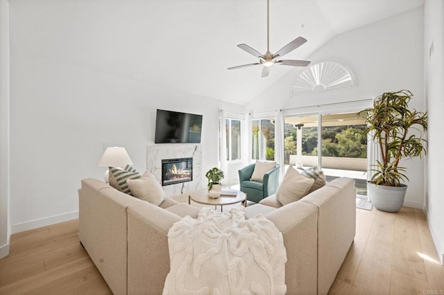 living room featuring ceiling fan, high vaulted ceiling, light wood finished floors, and a premium fireplace