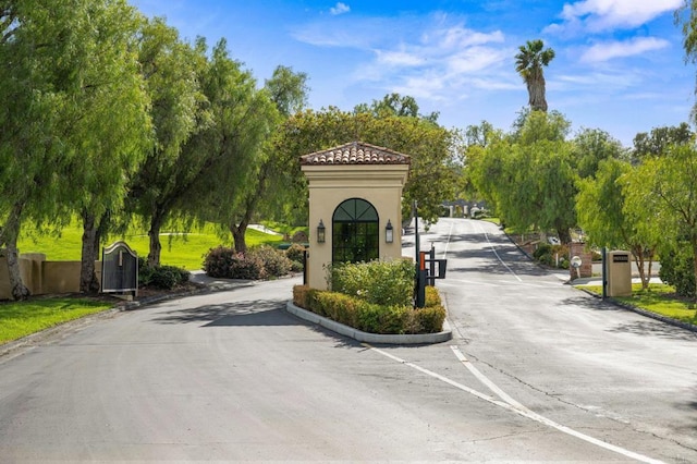 view of street with a gate, a gated entry, and curbs