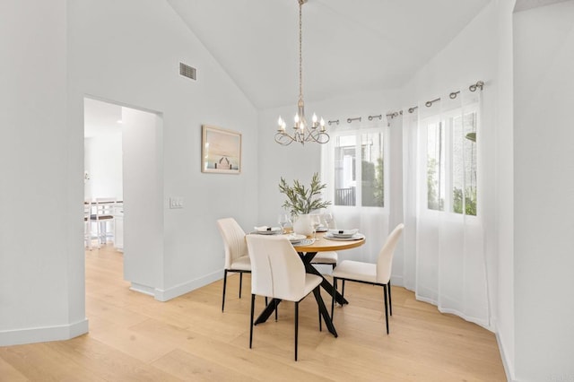 dining room with a chandelier, high vaulted ceiling, visible vents, baseboards, and light wood-type flooring