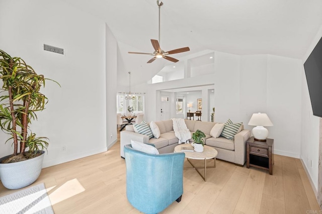 living area with ceiling fan with notable chandelier, high vaulted ceiling, visible vents, and light wood-style floors