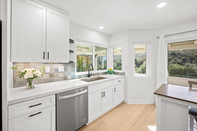 kitchen with a sink, a healthy amount of sunlight, decorative backsplash, and dishwasher