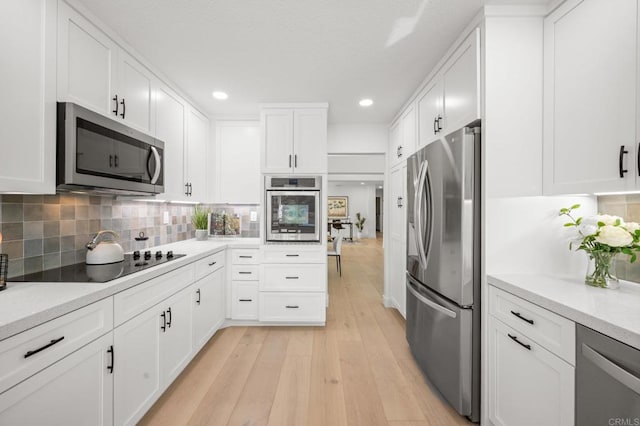 kitchen featuring tasteful backsplash, light countertops, appliances with stainless steel finishes, and light wood-style floors