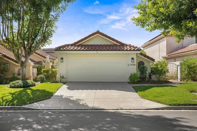 mediterranean / spanish home with a tile roof, driveway, an attached garage, and stucco siding