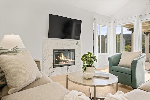 living room with lofted ceiling, wood finished floors, and a high end fireplace