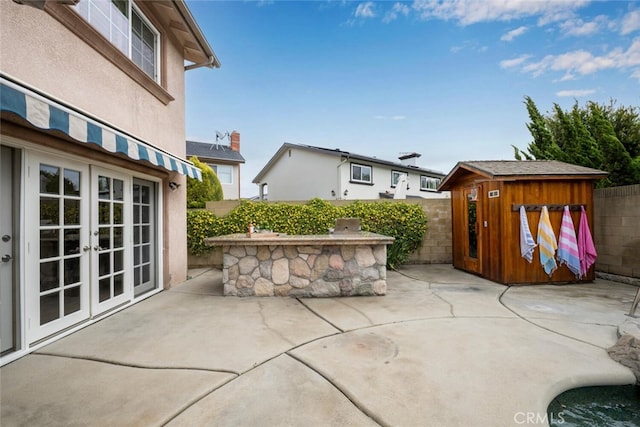 view of patio featuring a fenced backyard, a shed, french doors, and an outdoor structure