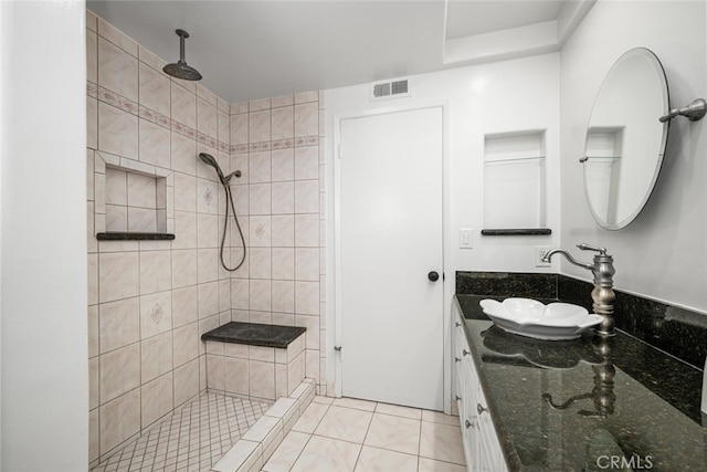 bathroom featuring visible vents, vanity, tile patterned flooring, and a tile shower