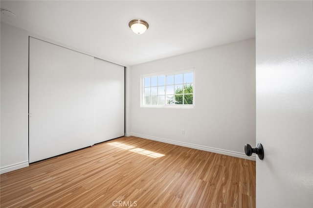 spare room featuring light wood finished floors and baseboards