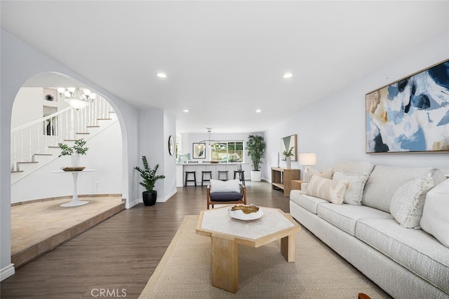 living area with dark wood-style floors, a notable chandelier, recessed lighting, and stairs