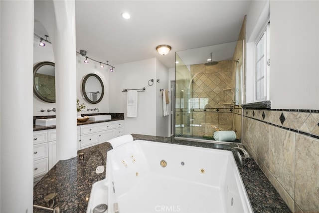 bathroom with a sink, a jetted tub, double vanity, and a shower stall