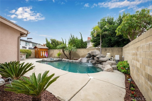 view of pool with a pool with connected hot tub, a storage shed, an outdoor structure, a fenced backyard, and a patio area