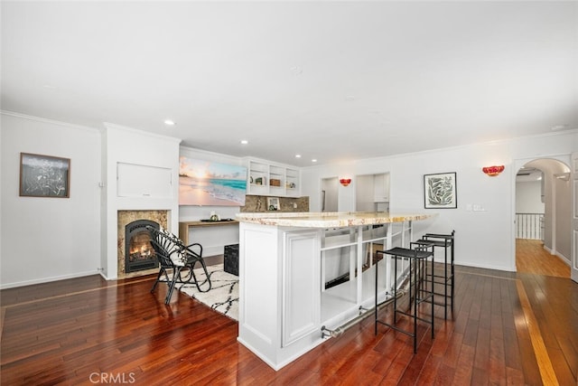 kitchen featuring arched walkways, dark wood finished floors, a kitchen breakfast bar, and open shelves