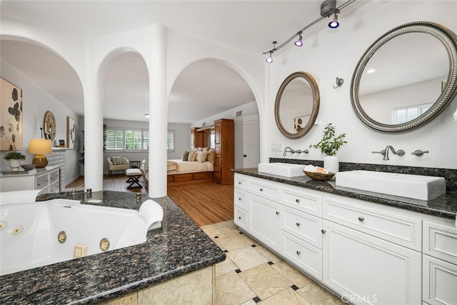 full bathroom with double vanity, a tub with jets, connected bathroom, and a sink