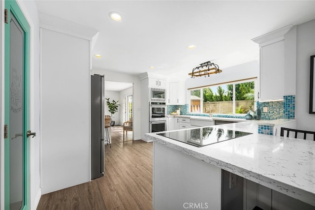 kitchen with a wealth of natural light, white cabinetry, appliances with stainless steel finishes, and tasteful backsplash