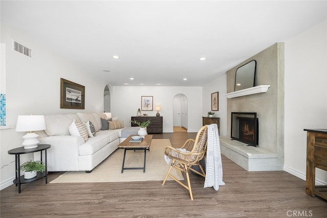 living room with visible vents, wood finished floors, recessed lighting, arched walkways, and a fireplace