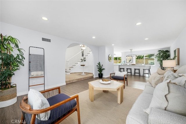 living room featuring visible vents, wood finished floors, recessed lighting, stairway, and arched walkways