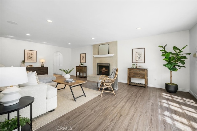 living area featuring a fireplace, recessed lighting, wood finished floors, and baseboards