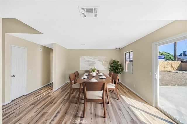 dining space with light wood-style flooring, visible vents, and baseboards