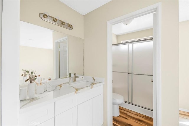 full bathroom with toilet, a stall shower, wood finished floors, and vanity