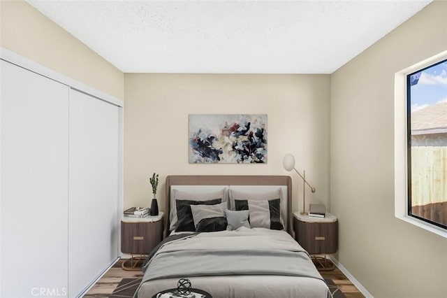 bedroom with a textured ceiling, a closet, baseboards, and wood finished floors